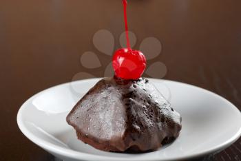 fresh baked chocolate cupcake with cherry on a wooden table