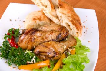 roasted chicken drumstick garnished with fresh green salad, pepper and greens