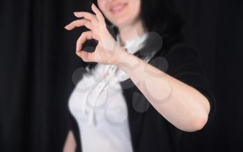 Woman at background indicating ok sign on a black background