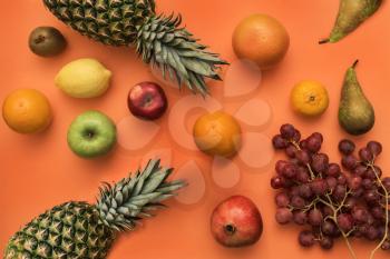 Different fruits, tangerine, pineapple, pears, grapes, apples lemon kiwi on bright color background