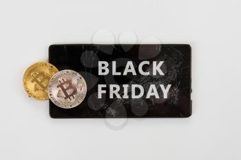 Bitcoin coins on the broken phone with Black friday sign