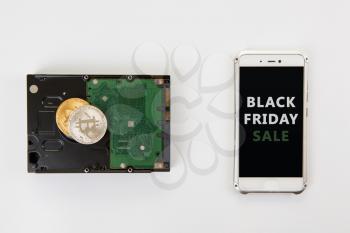 Bitcoin coins on the HDD and phone with Black Friday sign