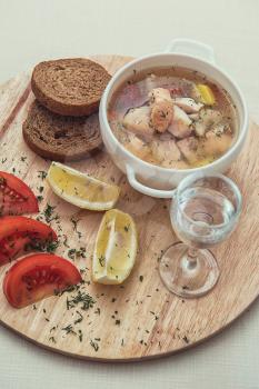 Russian traditional fish soup - ukha, served with bread lemon tomato and vodka