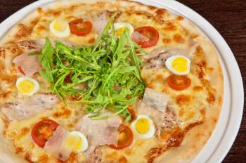 meat pizza with chicken, rukkola and eggs at the table