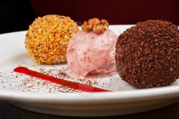 three scoops of ice cream desserts decorates with walnuts and chocolate