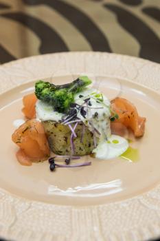 Potato casserole with broccoli white sauce and salmon fish decorated with micro greens sprouts of radish