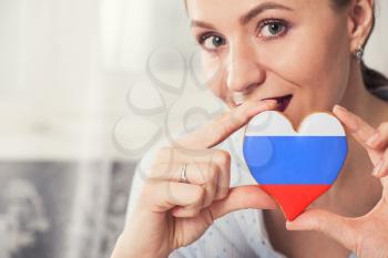Young woman with gingerbread heart cookies with flag of Russia
