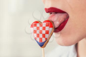 Closeup photo of the woman lips and cookie hearts with flag of Croatia
