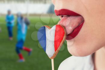 Closeup photo of the woman lips and cookie hearts with flag of France