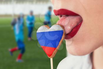 Closeup photo of the woman lips and cookie hearts with flag of Russia