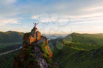 Travel, freedom leadership and real life concept - man standing on top of cliff in summer beauty sunset in Altai mountains