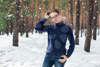 Portrait of pretty woman in a woolen blue sweater in the winter forest. Winter holidays concept or forest walking.