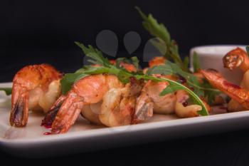 Fried shrimps with sauce and arugula on plate