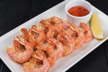 Fried shrimps with sauce and lemon on plate
