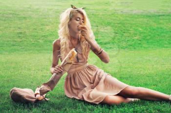 Rest in park, outdoor, people and food concept - beauty blonde young woman eating in the park