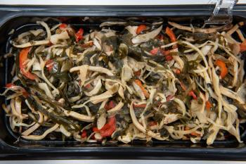 Chuka wakame laminaria seaweed salad with squid in plastic bowles. Concept of healthy food production or delivery food