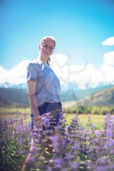 Happy young woman in beautiful wild pink and purple flowers field in summer Altai mountains