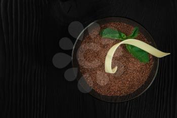 Delicious Italian dessert tiramisu, on a black wooden background decorated with mint leaf. Top view with copy space.