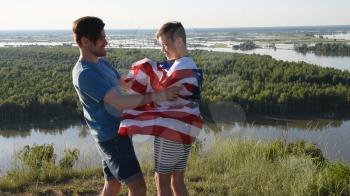Cute young boy and his father holding aloft the American flag in a patriotic gesture