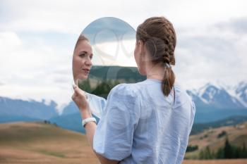 Man standing in in summer Altai mountains in Kurai steppe and holding circle mirror. Creative travel concept