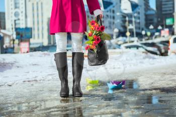 Woman wearing rain boots stay into a puddle