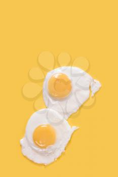 Fried eggs on yellow background