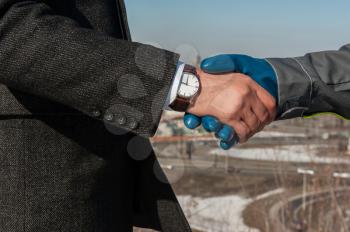 Industry worker with glove shakes hands with businessman