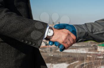 Industry worker with glove shakes hands with businessman