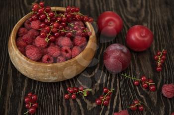 Fresh berries raspberry and red currant in bowl on wooden table