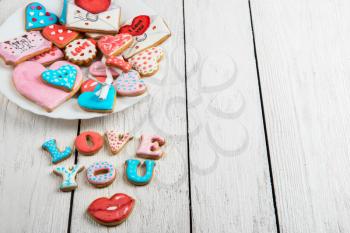 Gingerbreads for Valentines Day at plate on white wooden background
