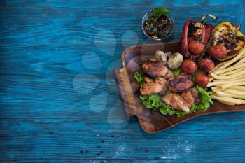Grilled pork meat with vegetable on a blue wooden background