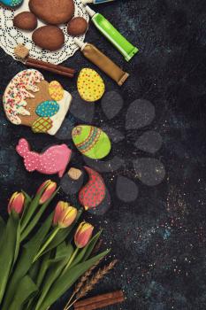 Tulips and gingerbread cookies on darken concrete background for Easter.