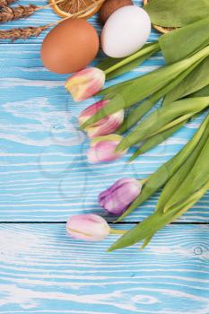 Tulips and gingerbread cookies on white and blue wooden background for Easter.