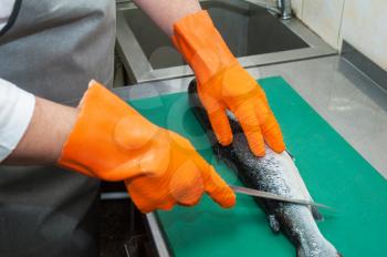 Chef cutting salmon fish with knife