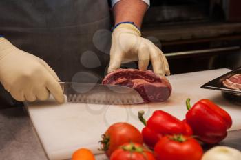 Chef cutting meat on steaks with knife