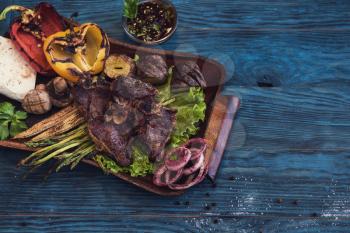 Grilled beef meat with vegetable on a blue wooden background