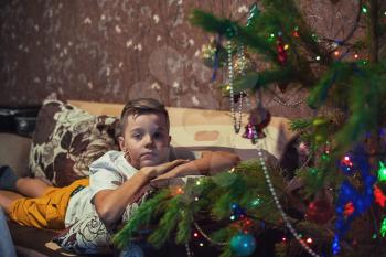 Sad boy portrait on New Year, xmas treen on background