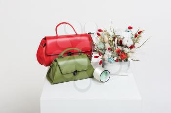 Red and green handbags and bouquet of dried flowers on white background