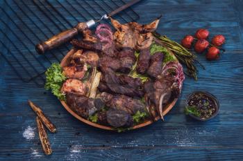 Grilled different meat with vegetable on a blue wooden background