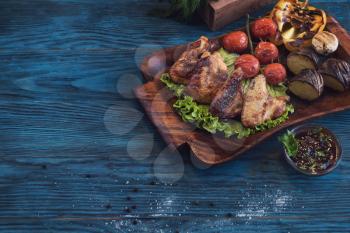 Grilled chicken meat with vegetable on a blue wooden background