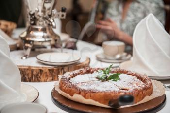 Apples pie with samovar on the served table