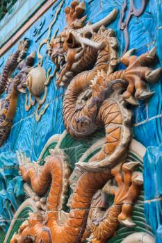 Detailed fragment of the Nine dragon wall in Beijing depicting yellow dragon figure among waves and clouds made from glazed tiles
