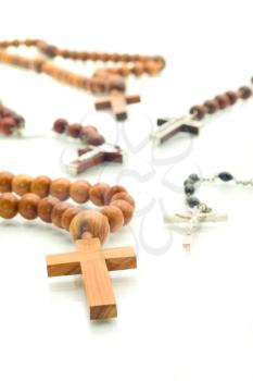 Religion diversity - rosary beads over white with focus on one cross (shallow DOF)