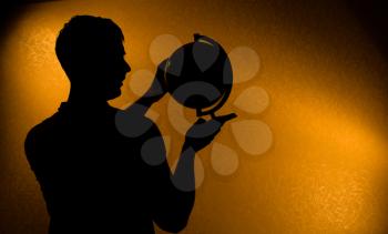 Your World - silhouette of man holding globe in the darkness