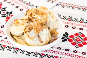 Ukrainian vareniki or dumplings with fried onion on traditional embroidered towel