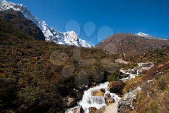 Himalayas landscape: snowed peaks and stream in autumn