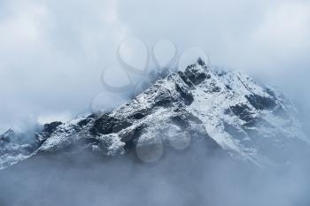Snowed Mountain peaks hidden in clouds in Himalayas. Travel to Nepal