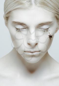 Hibernation and sleep: girl with closed eyes and insect on her cheek 