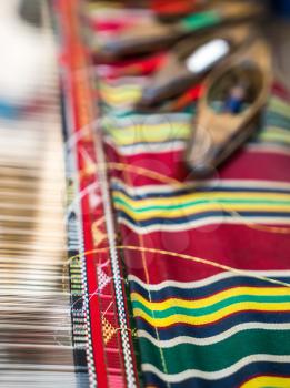 Weaving shuttles and textured textile with pattern. Artistic shallow DOF