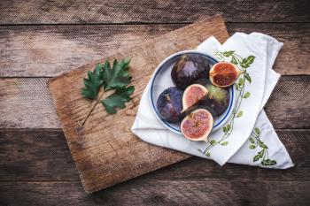 Figs in flat dish on choppingboard and napkin in rustic style. Autumn season food photo